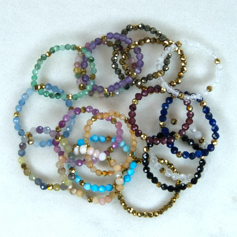 Gemstone rings in an overlapping arrangement of various colors on a white marble background