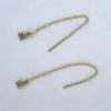 A set of yellow gold filled threader earrings with a 14K yellow gold authentic charm on spotted white marble background