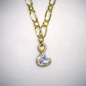 Close up of yellow gold filled courage necklace with gold vermeil polki diamond pendant on spotted white marble background