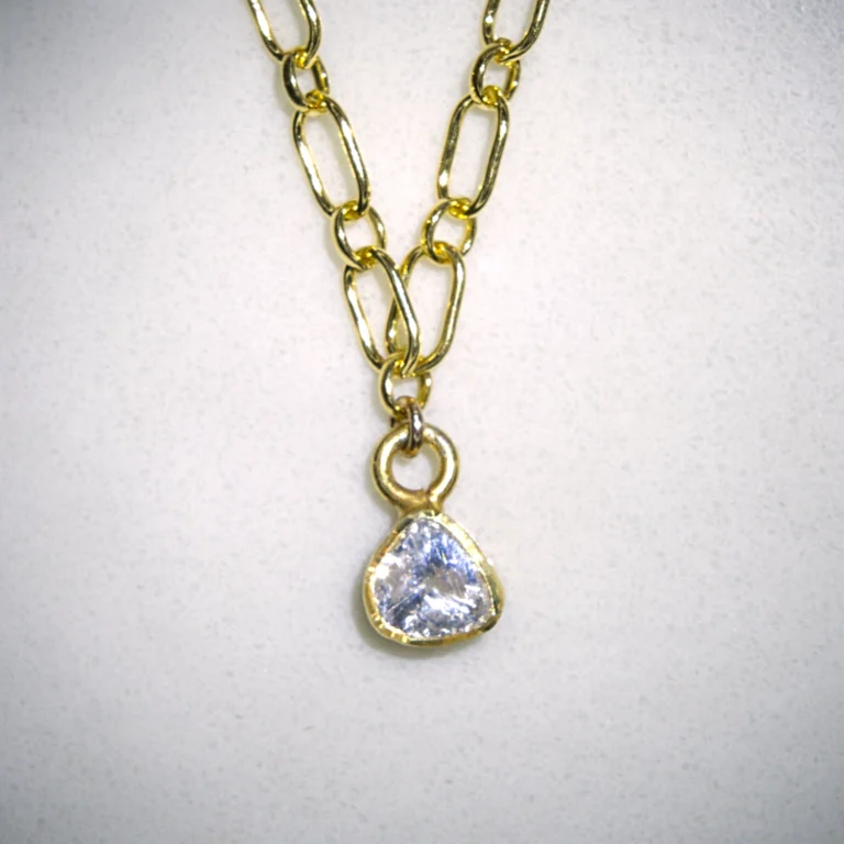 Close up of yellow gold filled courage necklace with gold vermeil polki diamond pendant on spotted white marble background