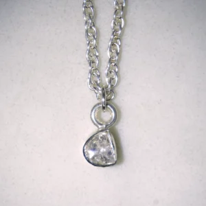 Close up of sterling silver double cable necklace with sterling silver polki diamond pendant on spotted white marble background