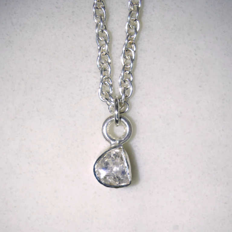 Close up of sterling silver double cable necklace with sterling silver polki diamond pendant on spotted white marble background