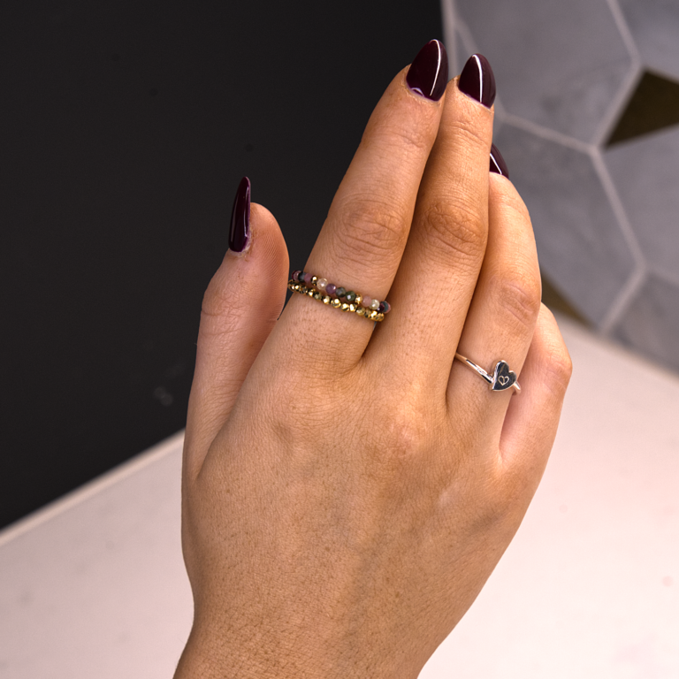 hand with sterling silver authentic ring and stacked gemstone tourmaline and gold dipped hematite rings with white, black and gray background