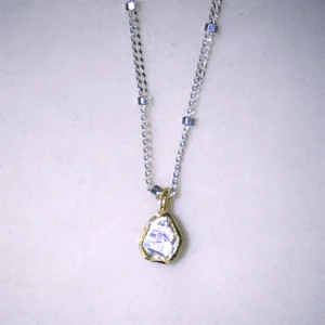 close up view sterling silver hope necklace with a gold vermeil polki diamond pendant on a white speckled background