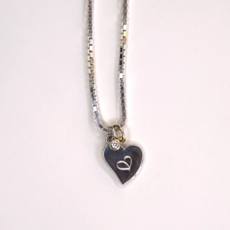 partial view sterling silver Venetian necklace with a sterling silver authentic heart pendant and a 14K yellow gold diamond pendant on white background